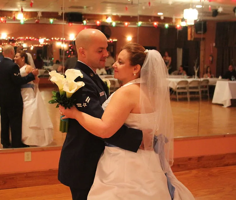A groom dancing with his bride, who is holding a bouquet of calla lilies