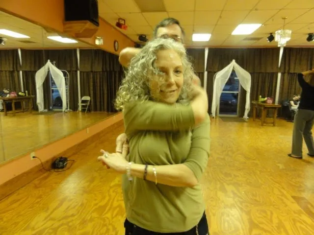A student in yellow being spun by her instructor