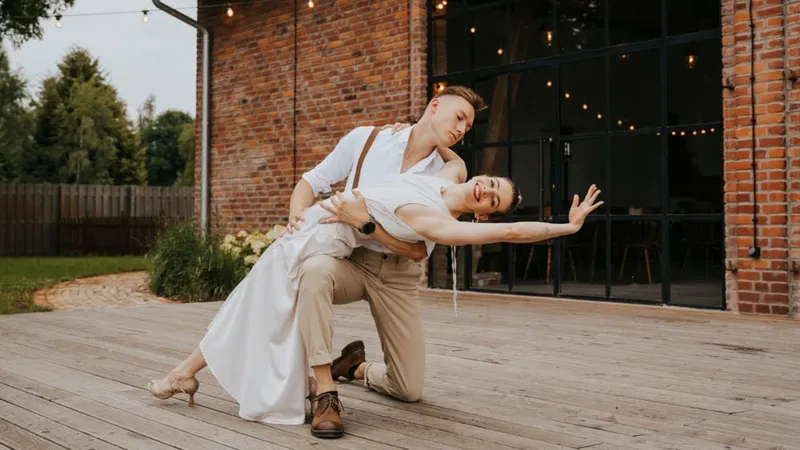 Two dancers in a deep lunge against a brick wall