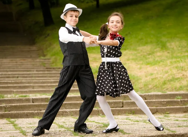 Two children in vintage dress dancing together outdoors