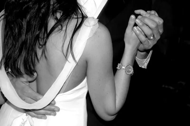 Black and white close-up of a couple’s clasped hands in a dance hold