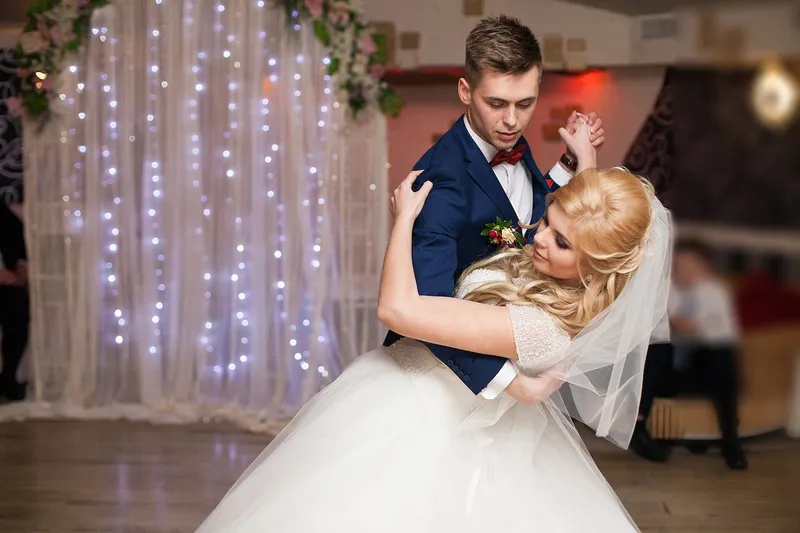 A groom dipping his bride in front of a curtain of lights