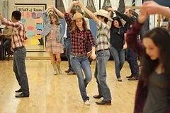A line of students in western wear practising together in a group class