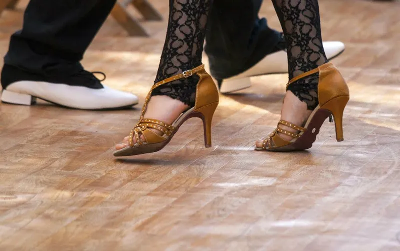 Close-up of two dancers’ feet in heels on a polished floor